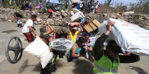 Colombian police help carry people's household belongings across the Tachira River on the border that separates San Antonio del Tachira, Venezuela from Villa del Rosario, Colombia, Aug. 25, 2015 (AP photo by Eliecer Mantilla).