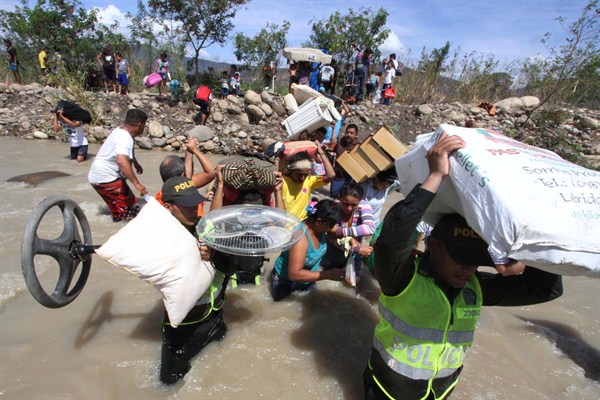 Colombian police help carry people's household belongings across the Tachira River on the border that separates San Antonio del Tachira, Venezuela from Villa del Rosario, Colombia, Aug. 25, 2015 (AP photo by Eliecer Mantilla).