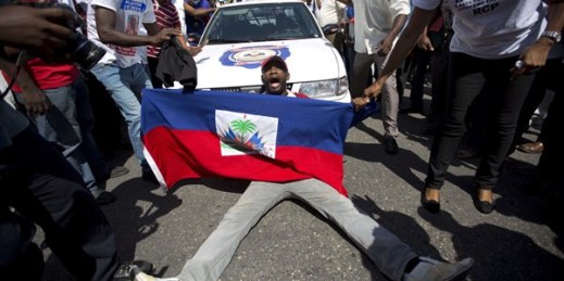 A demonstrator holding a Haitian flag blocks a police car during a march to protest the Dominican Republic's deportation of Haitians, Port-au-Prince, Haiti, July 21, 2015 (AP photo by Dieu Nalio Chery).
