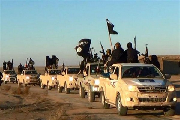 In this undated file photo, militants of the Islamic State group hold up their weapons and wave its flags on their vehicles in a convoy on a road leading to Iraq from Raqqa, Syria (Militant website via AP).