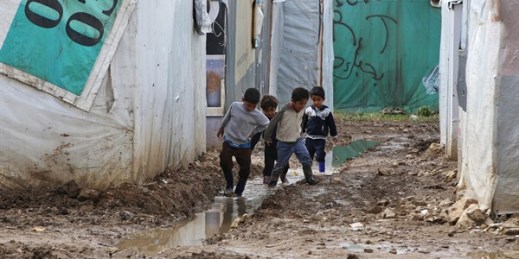 Syrian boys walk between tents in mud from the heavy rains at a refugee camp in the town of Marej in the Bekaa valley, east Lebanon, Feb. 25, 2015 (AP photo by Hussein Malla).