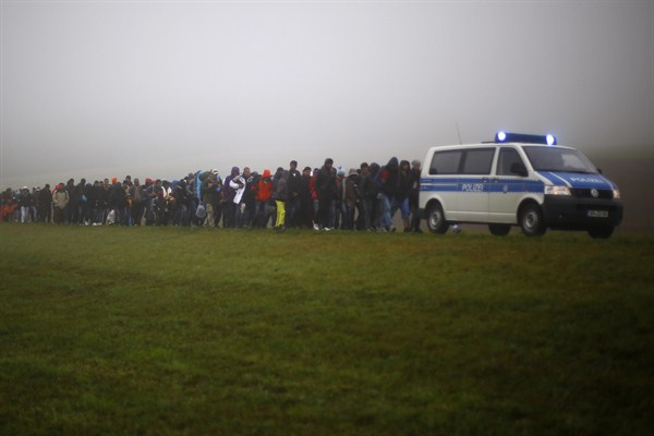 German federal police officers guide a group of migrants after crossing the border between Austria and Germany in Wegscheid, Germany, Oct. 15, 2015 (AP photo by Matthias Schrader).