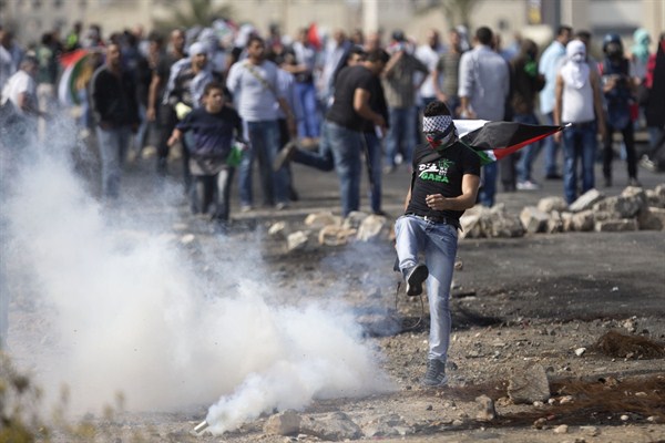 A Palestinian kicks a tear gas canister that was fired by Israeli troops during clashes near Ramallah, West Bank, Oct. 20, 2015 (AP photo by Majdi Mohammed).