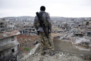 A Syrian Kurdish sniper looks at the rubble in the Syrian city of Kobani, Jan. 30, 2015 (AP photo).