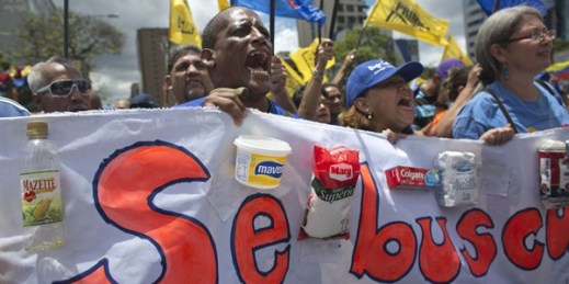 Protesters shout as they carry a banner featuring food products that are hard to find in grocery stores, with the Spanish words: "Wanted," Caracas, Venezuela, Aug. 8, 2015 (AP photo by Ariana Cubillos).