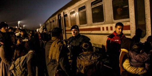 A Croatian Police officer controls a group of migrants while they board a train on the way to Slovenia within a temporary camp in Slavonski Brod, Croatia, Nov. 4, 2015 (AP photo by Manu Brabo).