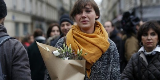A woman carrying flowers in front of the Carillon cafe and Petit Cambodge restaurant, Paris, France, Nov. 14, 2015 (AP photo by Jerome Delay).
