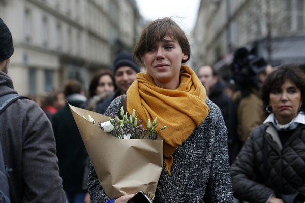 A woman carrying flowers in front of the Carillon cafe and Petit Cambodge restaurant, Paris, France, Nov. 14, 2015 (AP photo by Jerome Delay).