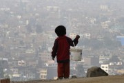 A child holds a bucket as he stands at the top of a hill in a poor neighborhood, Lima, Peru, May 15, 2008 (AP photo by Esteban Felix).