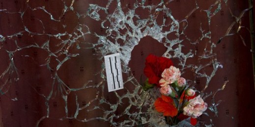 Flowers are put in a window shattered by a bullet in the Nov. 13 attacks, Paris, France, Nov. 15, 2015 (AP photo by Peter Dejong).