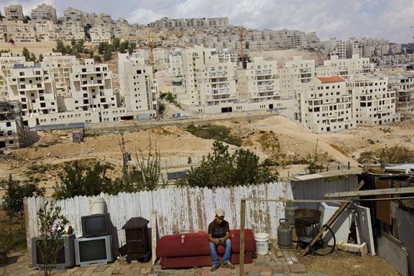 A Palestinian boy in front of an Israeli housing development, East Jerusalem, Sept. 21, 2009 (AP photo by Bernat Armangue).