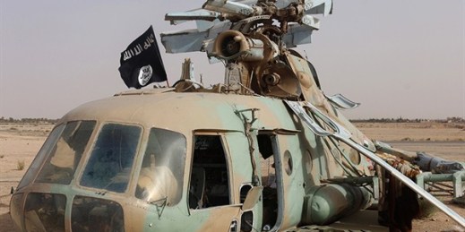 This photo released by a militant website shows a flag of the Islamic State group placed on a damaged helicopter, Tadmur military airbase, Palmyra, Syria, May 31, 2015 (Militant website via AP).