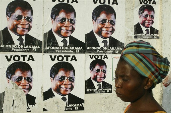 A woman walks past a campaign poster showing Afonso Dhlakama, presidential candidate for the Renamo party, Maputo, Mozambique, Nov. 30, 2004 (AP photo/STR).