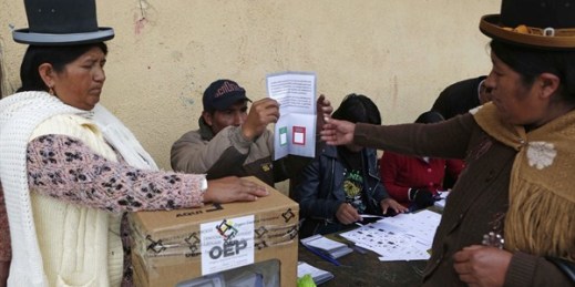 A delegate gives an unmarked ballot to a voter at a polling station during the constitution referendum, El Alto, Bolivia, Feb. 21, 2016 (AP photo by Juan Karita).
