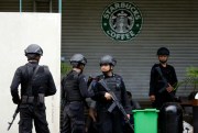 Indonesian police officers near a Starbucks cafe where suicide bombers blew themselves up, Jakarta, Jan. 16, 2016 (AP photo by Dita Alangkara).