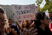 A woman holds a sign reading "For a transparent country, without secrets" during a demonstration against TPP, Santiago, Chile, Feb. 4, 2016 (AP photo by Esteban Felix).