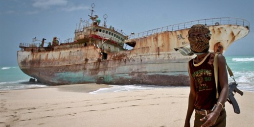 A masked Somali pirate near a Taiwanese fishing vessel that washed up on shore, Hobyo, Somalia, Sept. 23, 2012 (AP photo by Farah Abdi Warsameh).