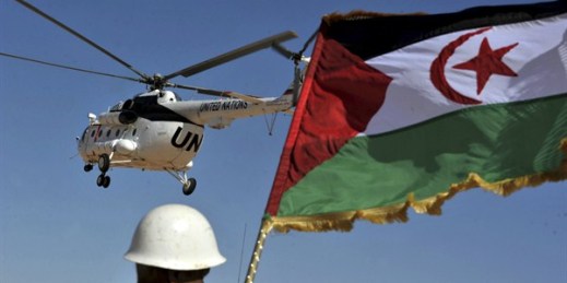 A soldier holds the Polisario Front flag as a U.N. helicopter flies over the Smara refugees camp, Tindouf, Algeria, March 5, 2016 (AP photo by Toufik Doudou).