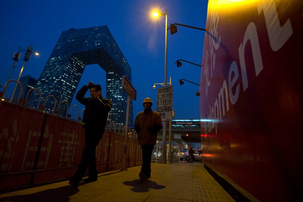 Chinese men next to a billboard with the word "Development" in the central business district, Beijing, China, Dec. 11, 2014 (AP photo by Ng Han Guan).