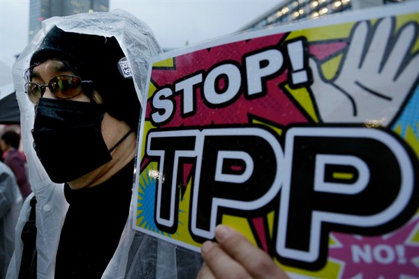 A protester holds a placard during a rally against the Trans-Pacific Partnership, Tokyo, Japan, Apr. 22, 2014 (AP photo by Shizuo Kambayashi).