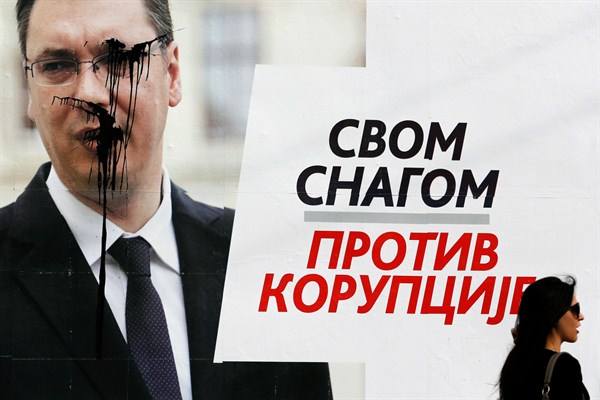 A girl passes by a vandalized campaign poster featuring Prime Minister Aleksandar Vucic with the slogan: "Strongly against corruption," Belgrade, Serbia, March 15, 2014 (AP photo by Darko Vojinovic).