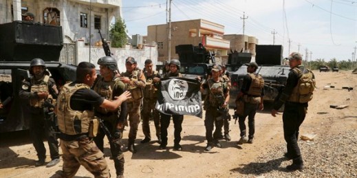 Iraqi counterterrorism forces hold an ISIS flag they captured regaining control of Hit, Iraq, April 13, 2016 (AP photo by Khalid Mohammed).
