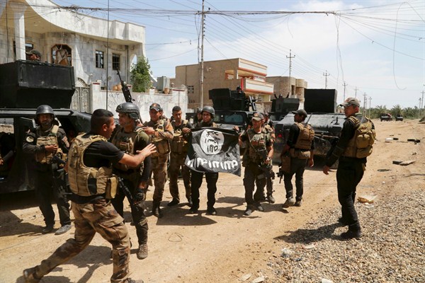Iraqi counterterrorism forces hold an ISIS flag they captured regaining control of Hit, Iraq, April 13, 2016 (AP photo by Khalid Mohammed).