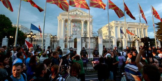 Protesters use a slingshot to throw balloons filled with colored paint on the main government building, Skopje, Macedonia, June 6, 2016 (AP photo by Boris Grdanoski).