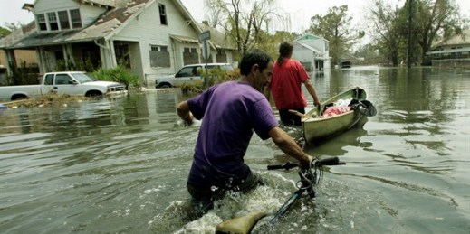 New Orleans residents push a small boat and a bicycle through floodwaters in the Ninth Ward, New Orleans, La., Sept. 5, 2005 (AP photo by Dave Martin).