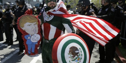 Erik Lopez, dressed as "Captain Mexico," stands in front of police officers while protesting Republican presidential candidate Donald Trump, Burlingame, California, April 29, 2016 (AP photo by Eric Risberg).