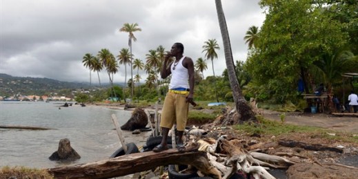A fisherman stands on a breakwater of old tires and driftwood that local residents made to protect their village, Telegraph, Grenada, April 22, 2013 (AP photo by David McFadden).