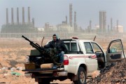 An anti-government rebel sits with an anti-aircraft weapon in front an oil refinery, Ras Lanouf, Libya, March 5, 2011 (AP photo by Hussein Malla).