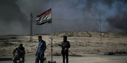 Guards at a checkpoint near burning oil fields in Qayara, south of Mosul, Iraq, Nov. 22, 2016 (AP photo by Felipe Dana).