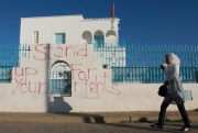A woman walks past graffiti in Sidi Bouzid, where the protests that lit the Arab world began, Tunisia, Oct. 19, 2011 (AP photo by Amine Landoulsi).