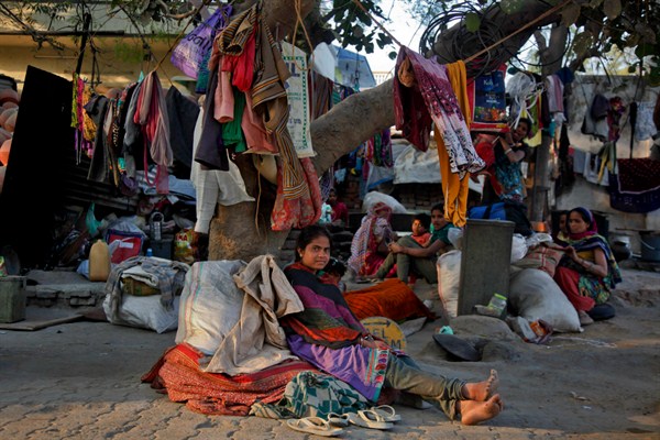 Clothes and other belongings of Indian laborers hang from a tree where they live on a roadside, Ahmadabad, India, Jan. 19, 2016 (AP photo by Ajit Solanki).