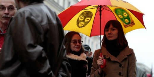 A woman carries an umbrella with pictures of masked members of the Russian punk band Pussy Riot during an opposition rally, Moscow, Oct. 27, 2013 (AP photo by Ivan Sekretarev).