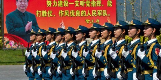 Chinese female troops marching near a billboard showing President Xi Jinping and Communist Party slogans, at a camp on the outskirts of Beijing, Aug. 22, 2015 (AP photo by Ng Han Guan).