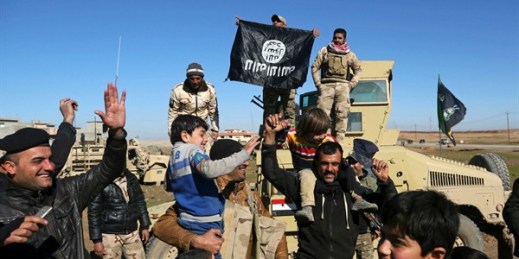 Iraqi Army soldiers celebrate with residents of liberated neighborhoods as they hold upside down a flag of the Islamic State, eastern Mosul, Iraq, Jan. 24, 2017 (AP Photo by Khalid Mohammed).