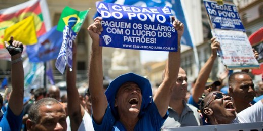 A demonstrator holds up a sign that reads in Portuguese "CEDAE belongs to the people," during a protest against a move to privatize the state water and sewage company, CEDAE, Rio de Janeiro, Brazil, Feb. 20, 2017 (AP photo by Leo Correa).