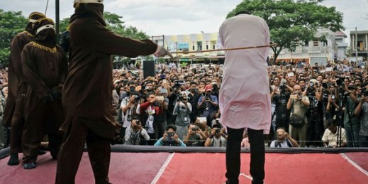 An official tasked with enforcing Shariah strikes one of two men convicted of gay sex during a public caning, Banda Aceh, Indonesia, May 23, 2017 (AP photo by Heri Juanda).