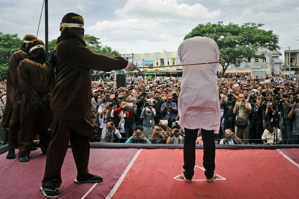 An official tasked with enforcing Shariah strikes one of two men convicted of gay sex during a public caning, Banda Aceh, Indonesia, May 23, 2017 (AP photo by Heri Juanda).