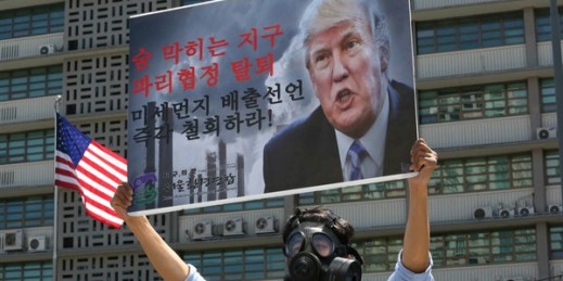 A South Korean environmental activist wearing a gas mask and bearing a sign denouncing the U.S. withdrawal from the Paris climate accord participates in a protest in front of the U.S. Embassy, Seoul, June 5, 2017 (AP photo by Ahn Young-joon).