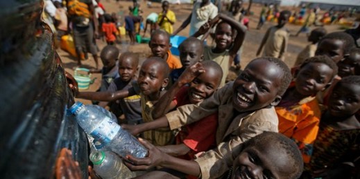 South Sudanese refugee children catch water overflowing from a reservoir being filled at the Imvepi reception center, northern Uganda, June 9, 2017 (AP photo by Ben Curtis).