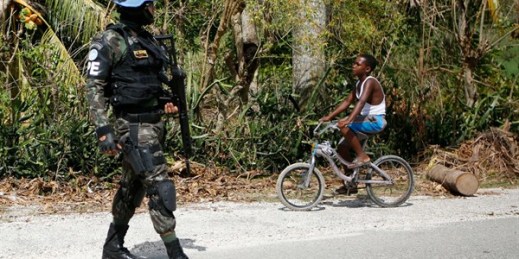 A boy bikes past a U.N. soldier from Brazil on the road between Port-au-Prince and Les Cayes, Haiti, Oct. 15, 2016 (AP photo by Rebecca Blackwell).