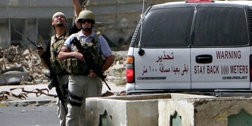 Private contractors secure the scene of a roadside bomb attack in Baghdad, Iraq, July 5, 2005 (AP photo by Khalid Mohammed).