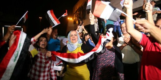 Iraqis celebrate while holding national flags in Baghdad’s Tahrir Square after Prime Minister Haider al-Abadi declared victory against the Islamic State group in Mosul, July 10, 2017 (AP photo by Karim Kadim).