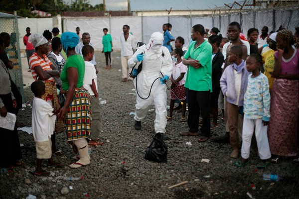A medical worker sprays people being discharged from the Island Clinic Ebola treatment center, Monrovia, Liberia, Sept. 30, 2014 (AP photo by Jerome Delay).
