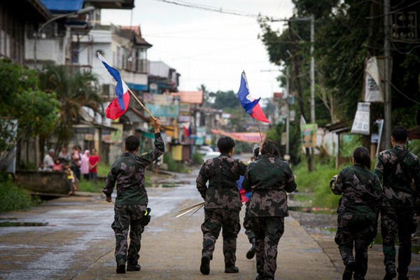 Philippine National Police hang flags in a part of the war-torn city of Marawi ahead of Independence Day celebrations, June 11, 2017 (NurPhoto by Richard Atrero de Guzman via AP).