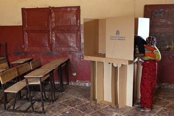 A woman with a child on her back casts her ballot at a voting station, Luanda, Angola, Aug. 31, 2012 (AP photo).