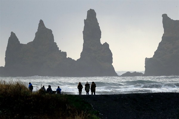 People walk on a beach near the volcano Katla, a tourism hotspot, Vik, Iceland, Oct. 26, 2016 (AP photo by Frank Augstein).